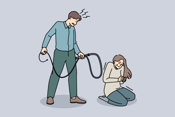 Mężczyzna znęca się nad kobietą. Kobieta jest skulona, wystraszona i płacze