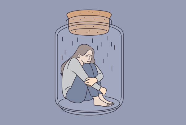 Smutna kobieta siedzi zamknięta w słoju, co obrazuje poczucie odizolowania od innych.