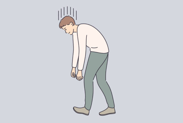 Zmęczony mężczyzna z pochyloną sylwetką od ciężaru presji perfekcjonizmu.